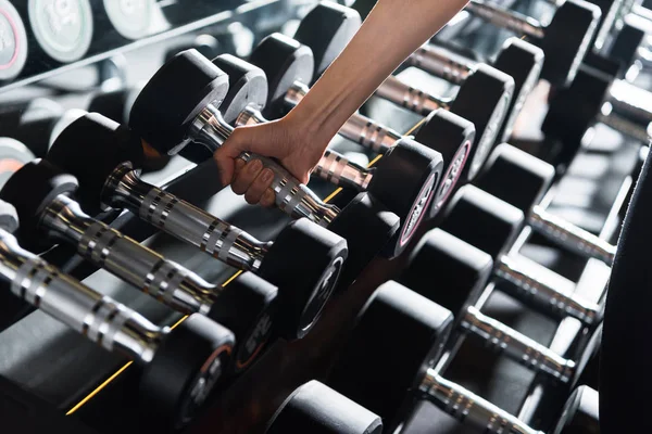 stock photo cropped view athletic young woman taking heavy dumbbell gym